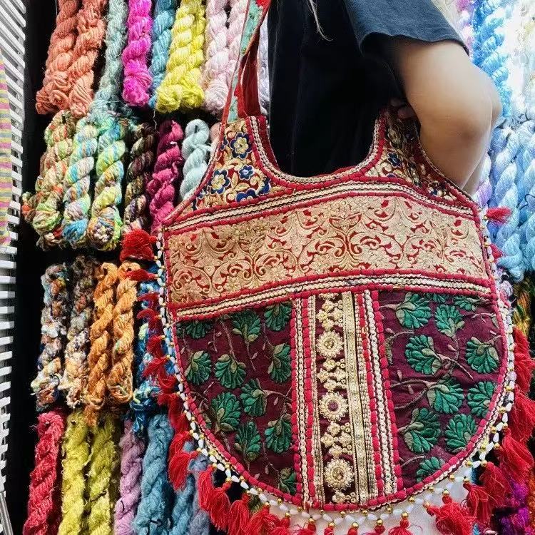 Red embroidered shoulder bag with floral details and tassels